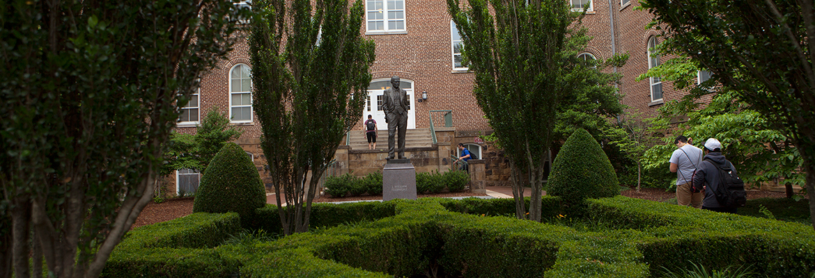 Uark student with blue skies and Old Main in the background