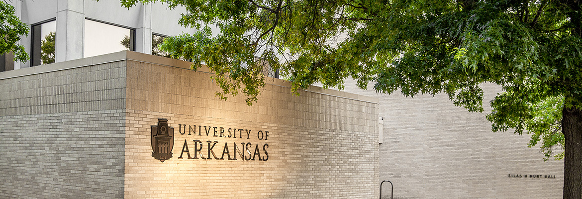 Uark student with blue skies and Old Main in the background