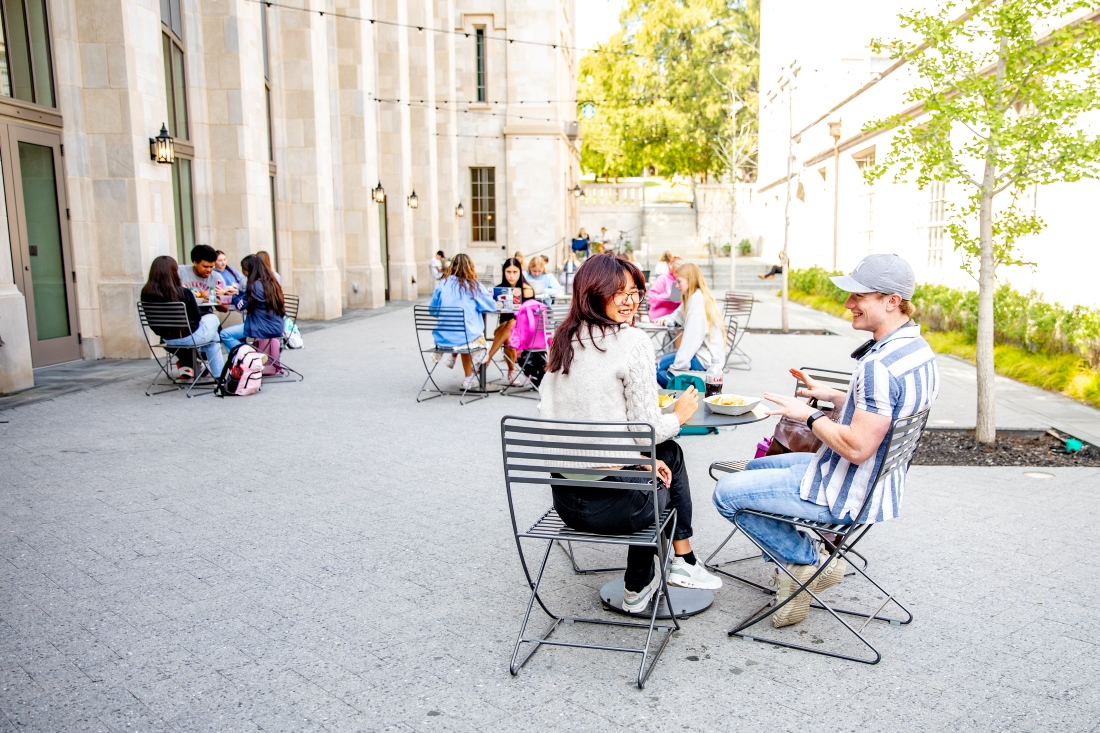 Uark student with blue skies and Old Main in the background